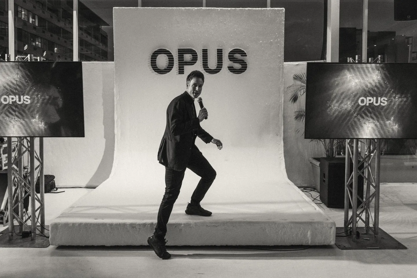 Speaker stepping across a white OPUS stage set with a microphone