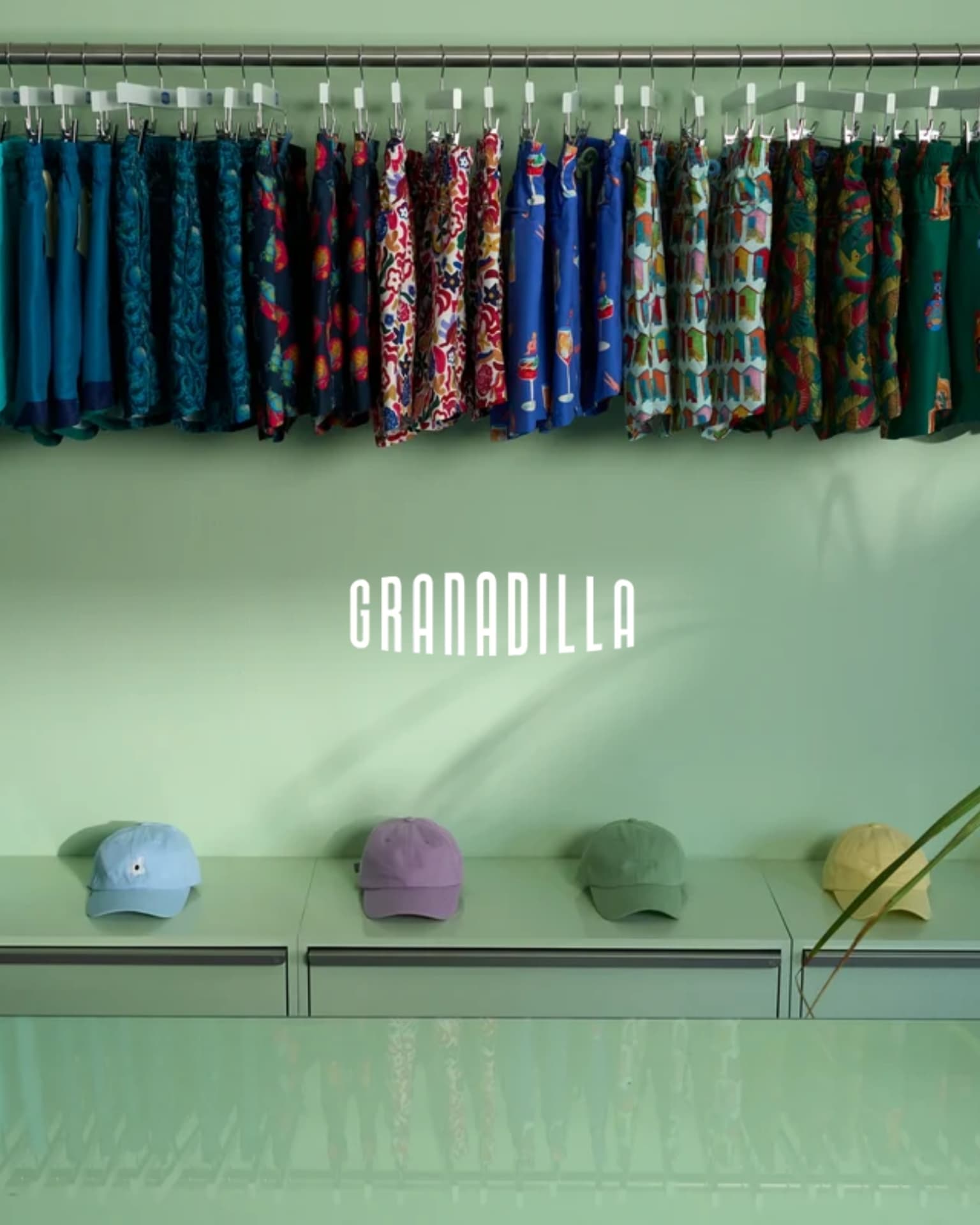 Granadilla store interior with a rail of printed swim shorts and caps below the wordmark