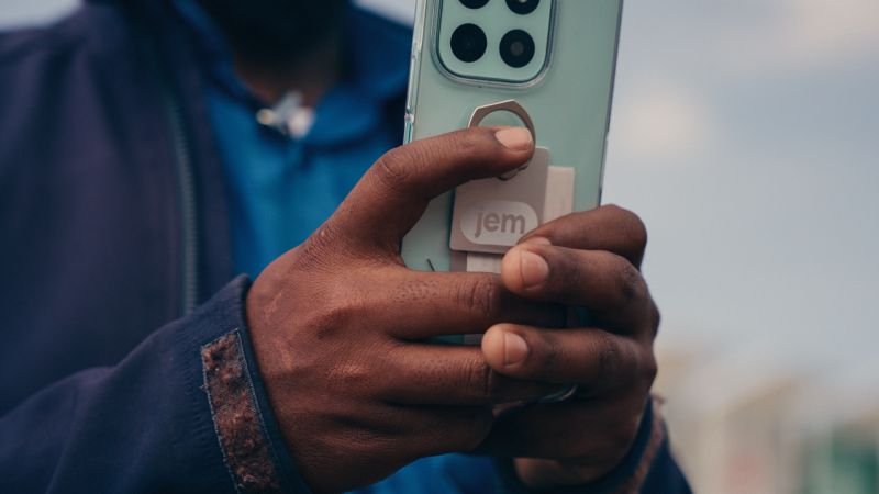 A Jem tag attached to the back of a phone held outdoors