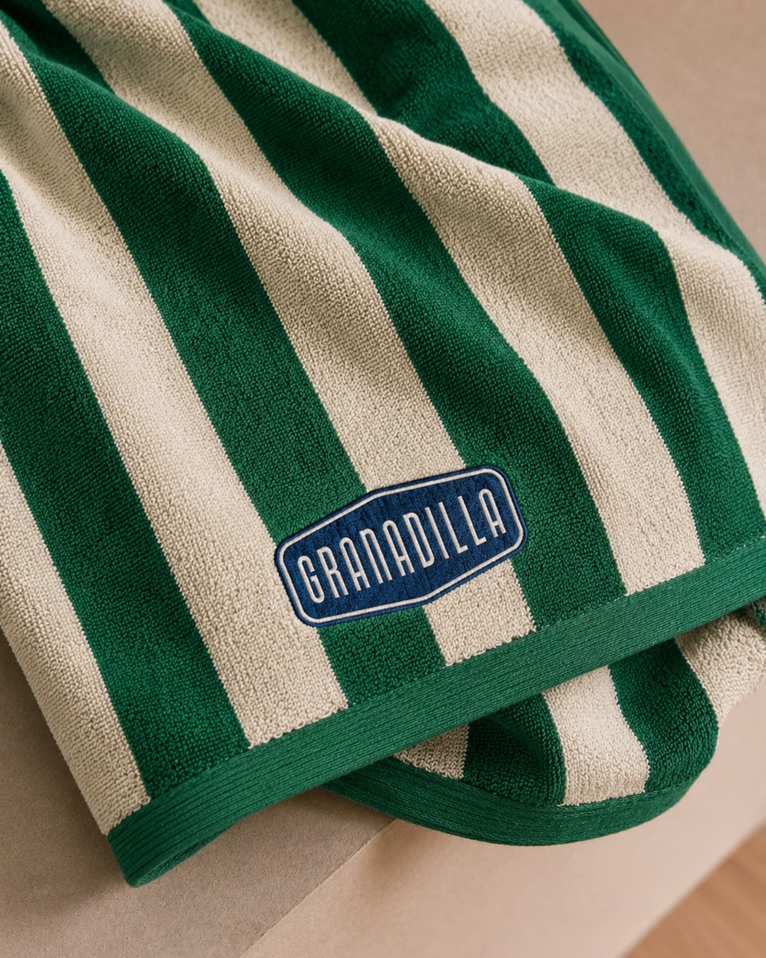 Green and cream striped Granadilla towel with an embroidered logo badge