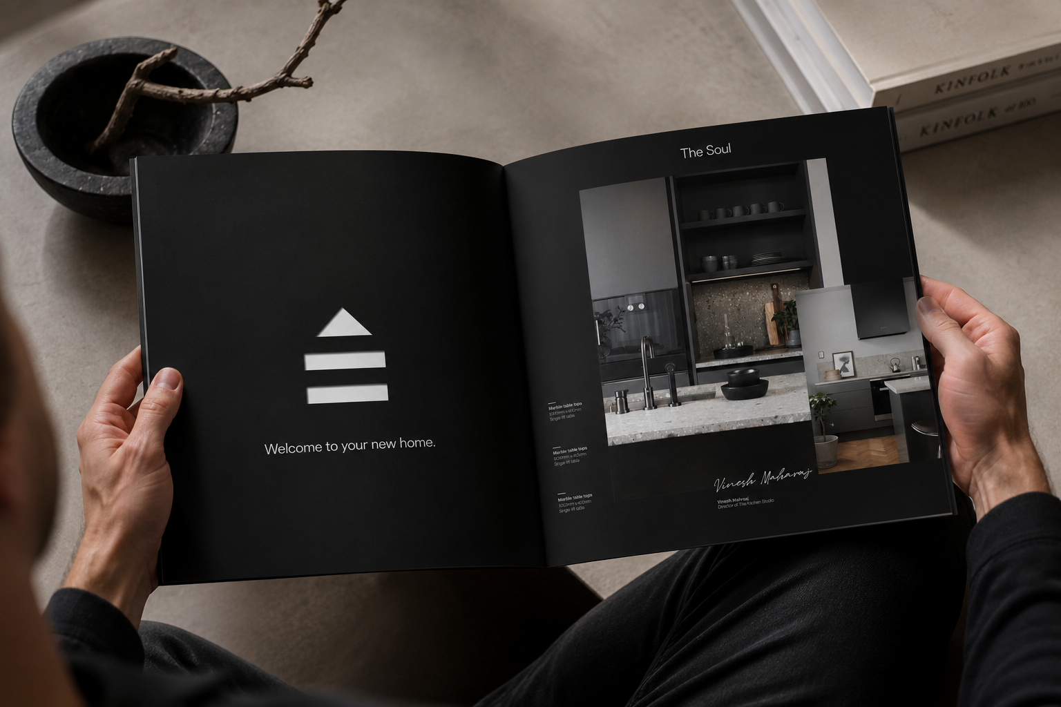 Hands holding The Kitchen Studio black brochure open on a spread
