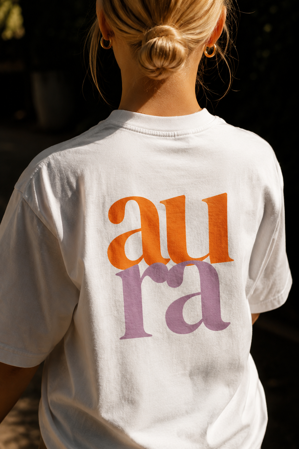 Aura logo printed in orange and lilac on the back of a white t-shirt