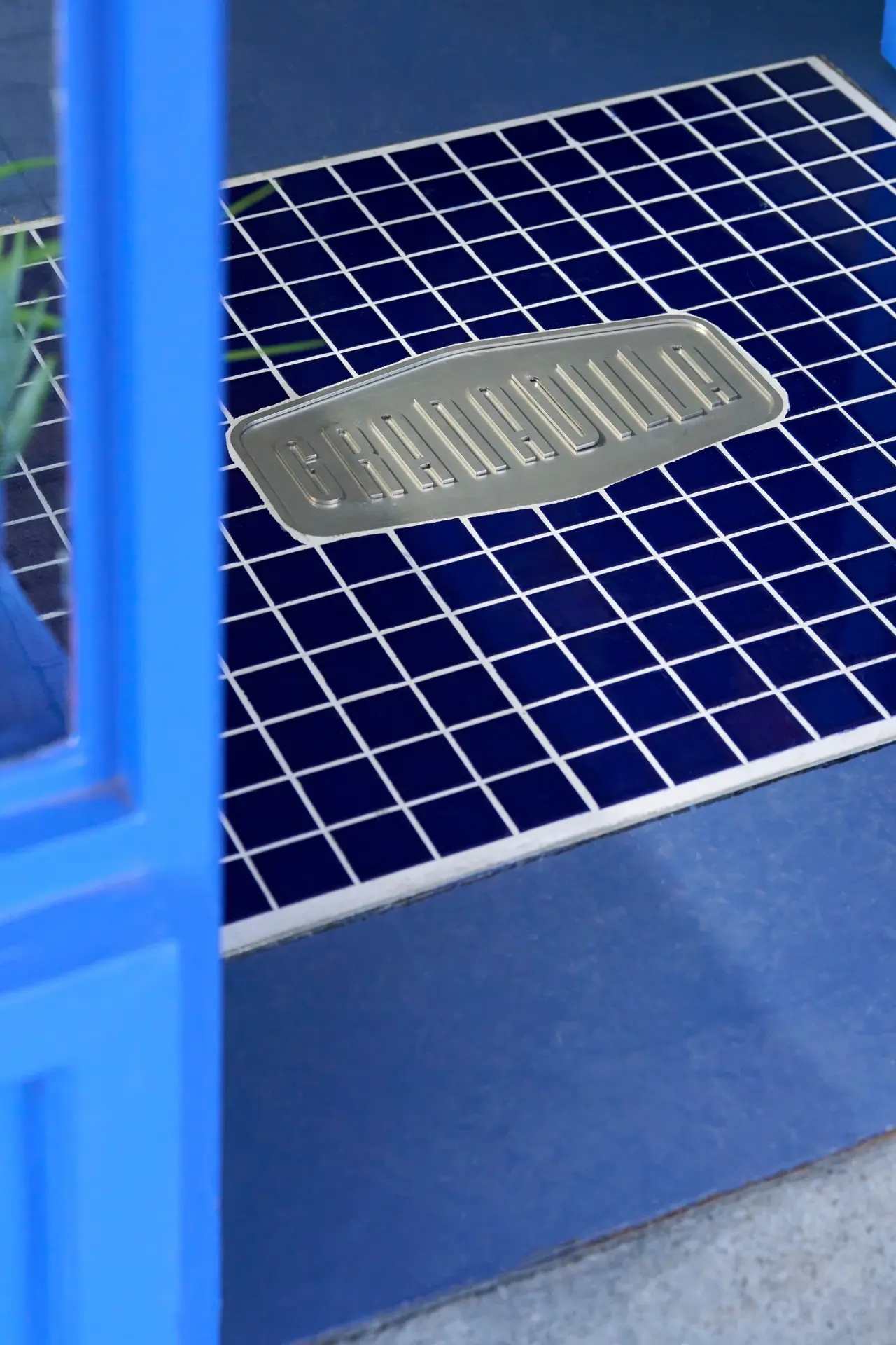Granadilla store entrance with a metal wordmark plaque set into cobalt tiling