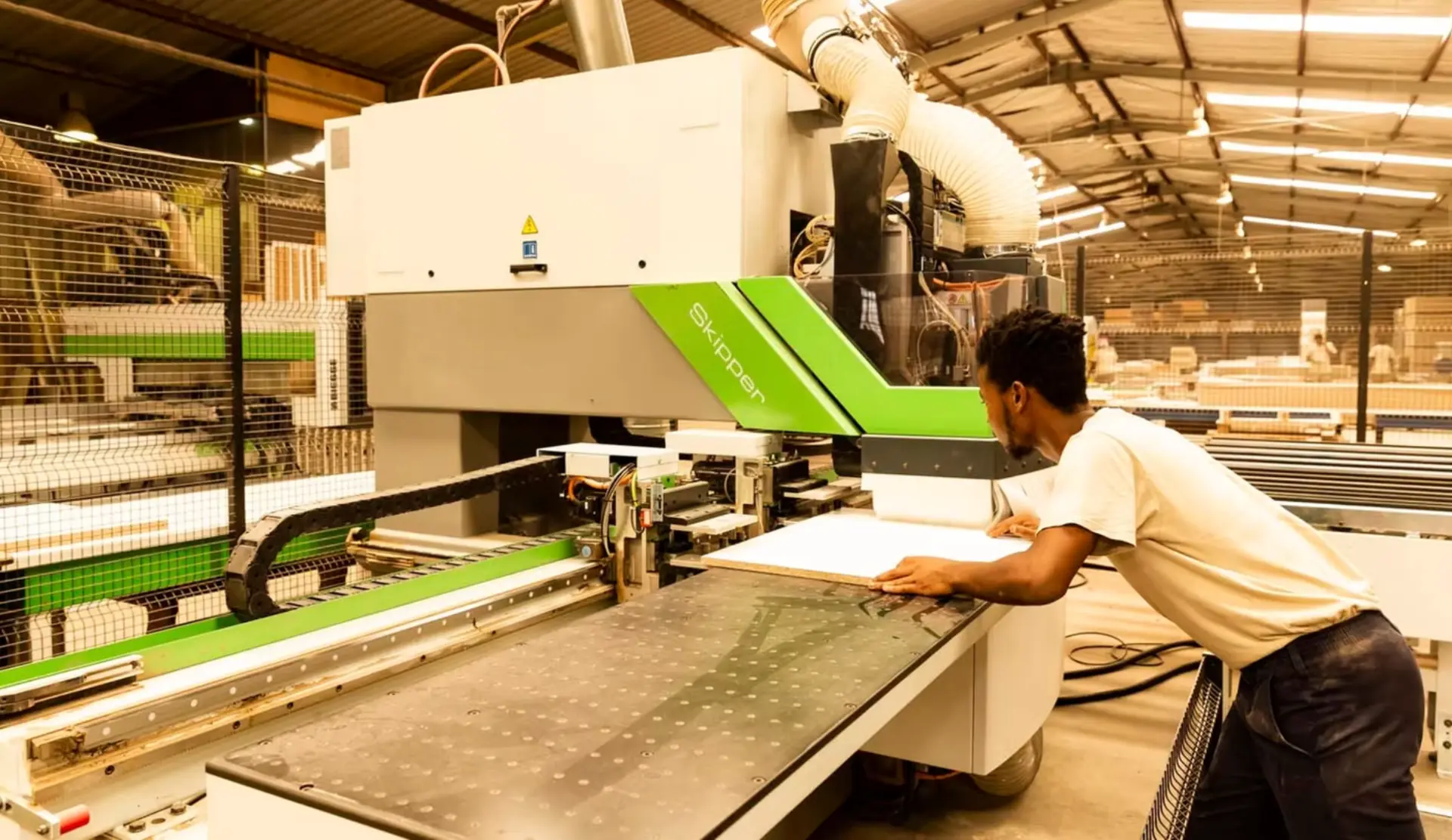 A Kitchen Studio craftsman feeding a board into a CNC machine on the factory floor